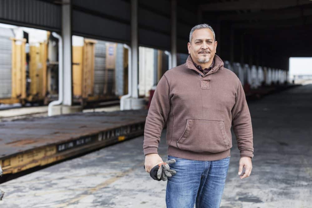 A man on workers’ comp standing in front of a warehouse.