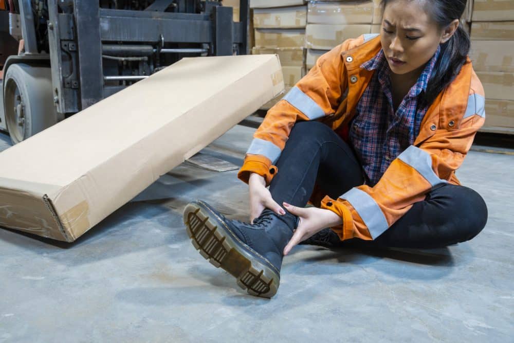 An injured warehouse worker holding her injury in pain.