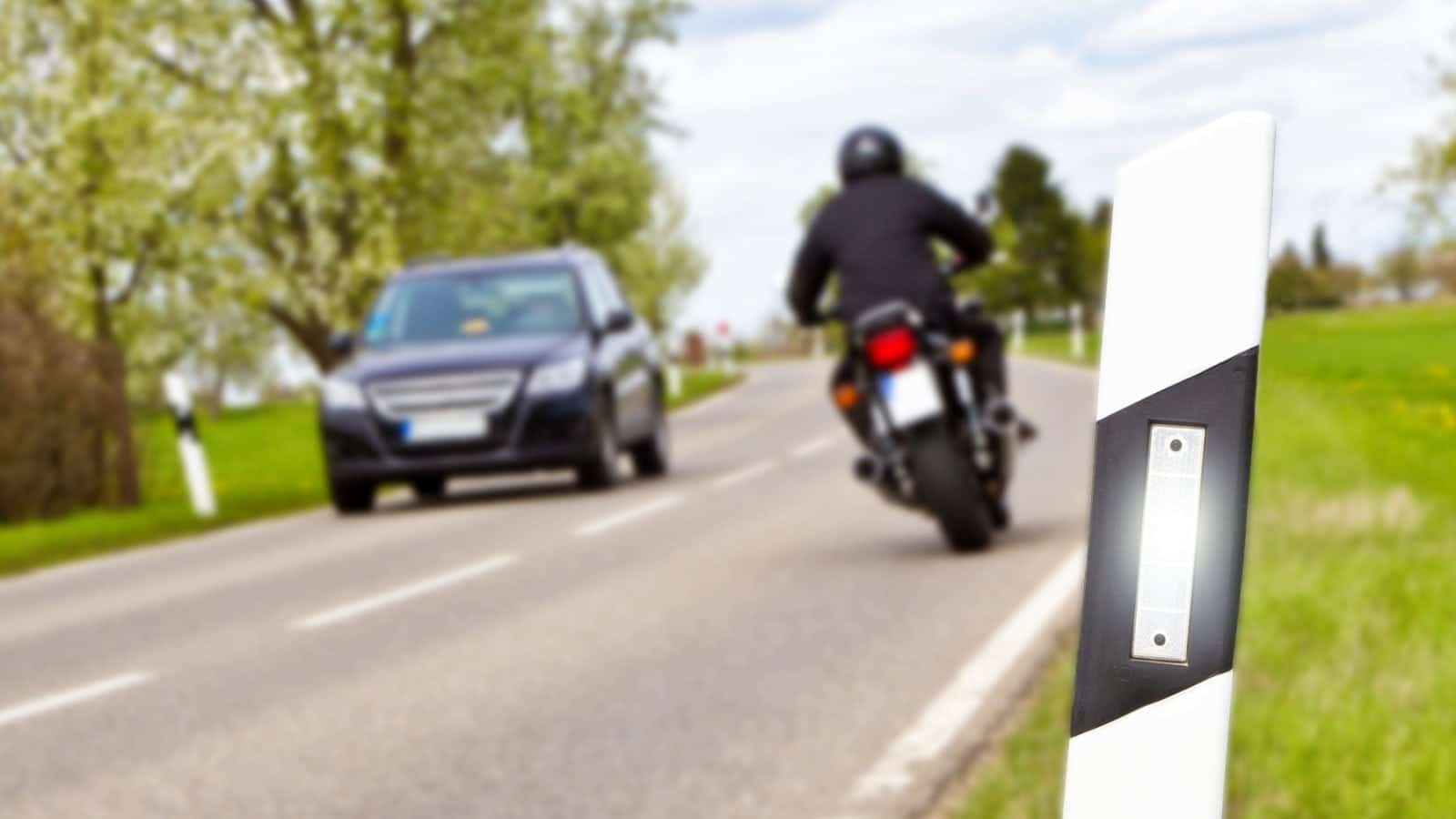 Motorcyclist Passing A Car On A Rural Road Stock Photo